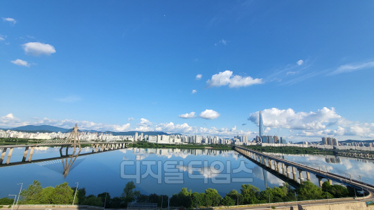 부처님 오신날 황금연휴. 지리하게 내린 빗줄기 만큼이나 아쉬움이 컸다. 한꺼번에 보상하려 했던 것일까. 대체공휴일이자 연휴 마지막날인 29일, 자연은 파아란 하늘을 선물했다. 시리도록 파란 하늘에 자칫 눈을 다칠까 걱정한 때문일까.  희디 흰 구름꽃 몇 송이도 살포시 올려놓았다. 한강은 그 하늘을, 그리고 인간의 탐욕마저  온몸으로 감싸안았다.  서울 광진구 구의동 테크노마트 하늘정원. 강건너 롯데타워와 잠실 아파트 단지, 그리고 한강을 남북으로 잇는 잠실철교의 모습을 휴대전화 카메라에 담았다.           독자 김용진 씨 제공